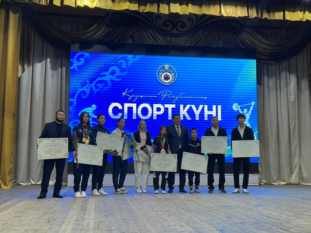 Қазақстан Республикасының Спорт күніне арналған марапаттау рәсімі: жеңімпаздар сертификаттармен сахнада тұр.