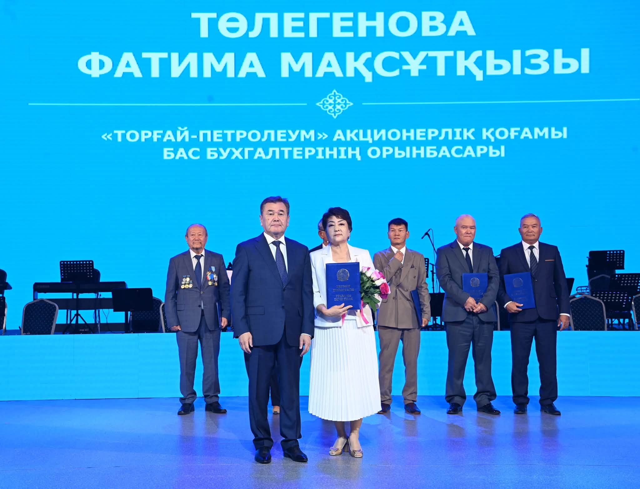 Сыйлықты алып жатқан Фатима Төлегенова мен сахнадағы құрметті қонақтар.