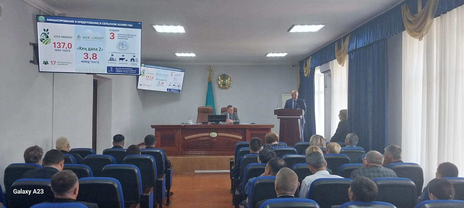Экранда презентация, трибунада баяндамашы және тыңдаушылар.