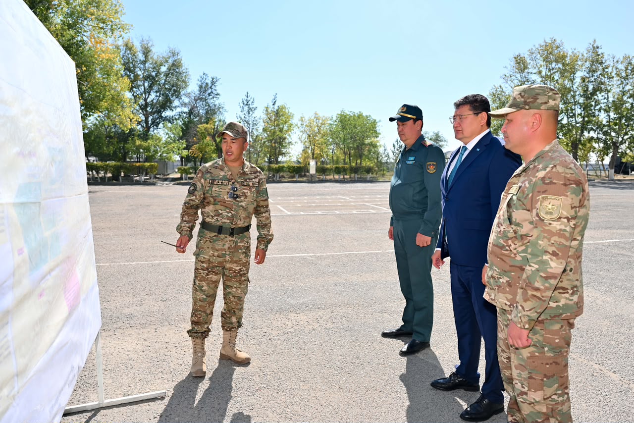Әскери формадағы сарбаз карта бойынша ресми киінген адамдар мен әріптестеріне түсіндіру беріп жатыр.