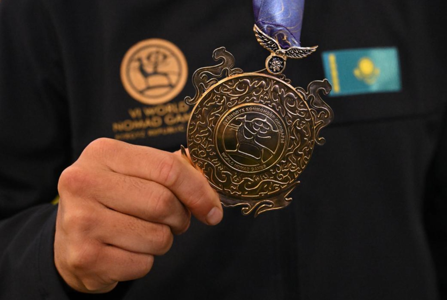Қолында Әлемдік көшпенділер ойындарының алтын медальін ұстаған спортшы.