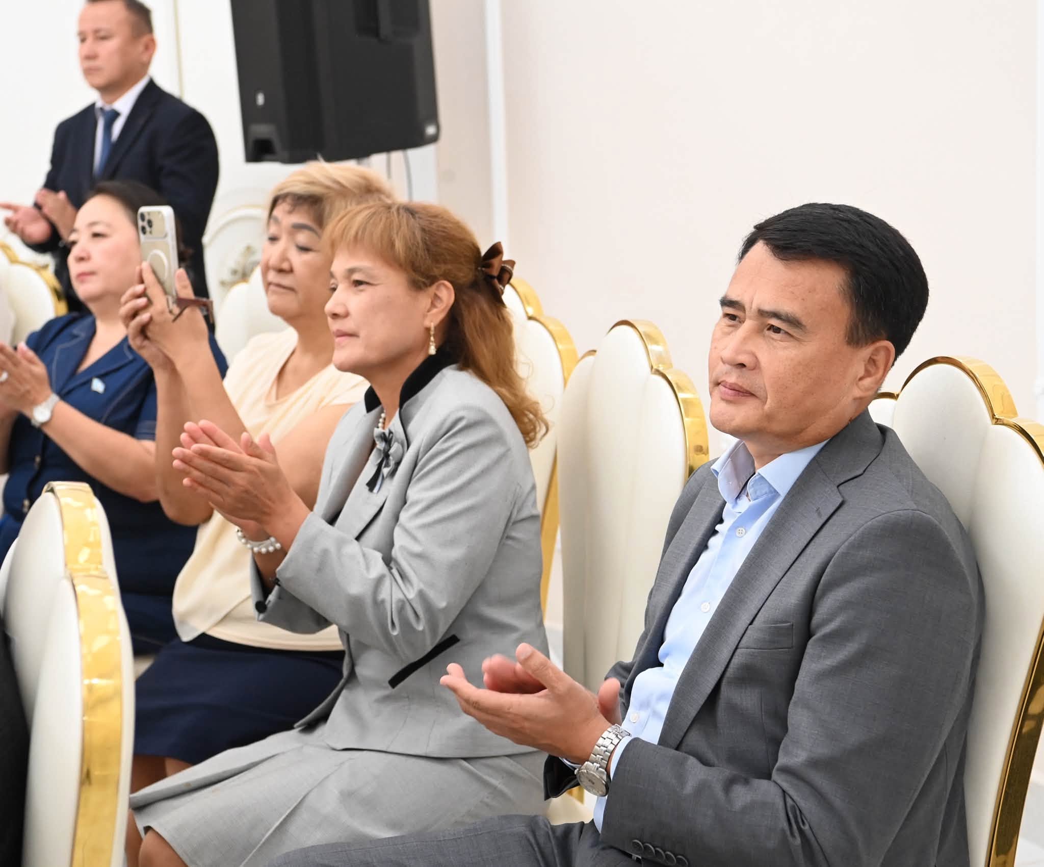 Шараға қатысушылардың алтында отырып, қол шапалақтап жатқан сәті.