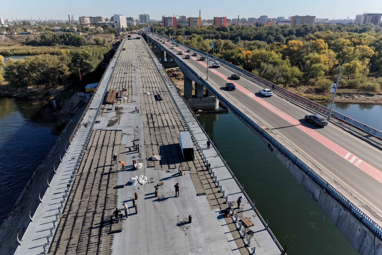 Жөнісіп жатқан көпір мен қасындағы жұмыс істеп тұрған көлік жолының жоғарыдан көрінісі.