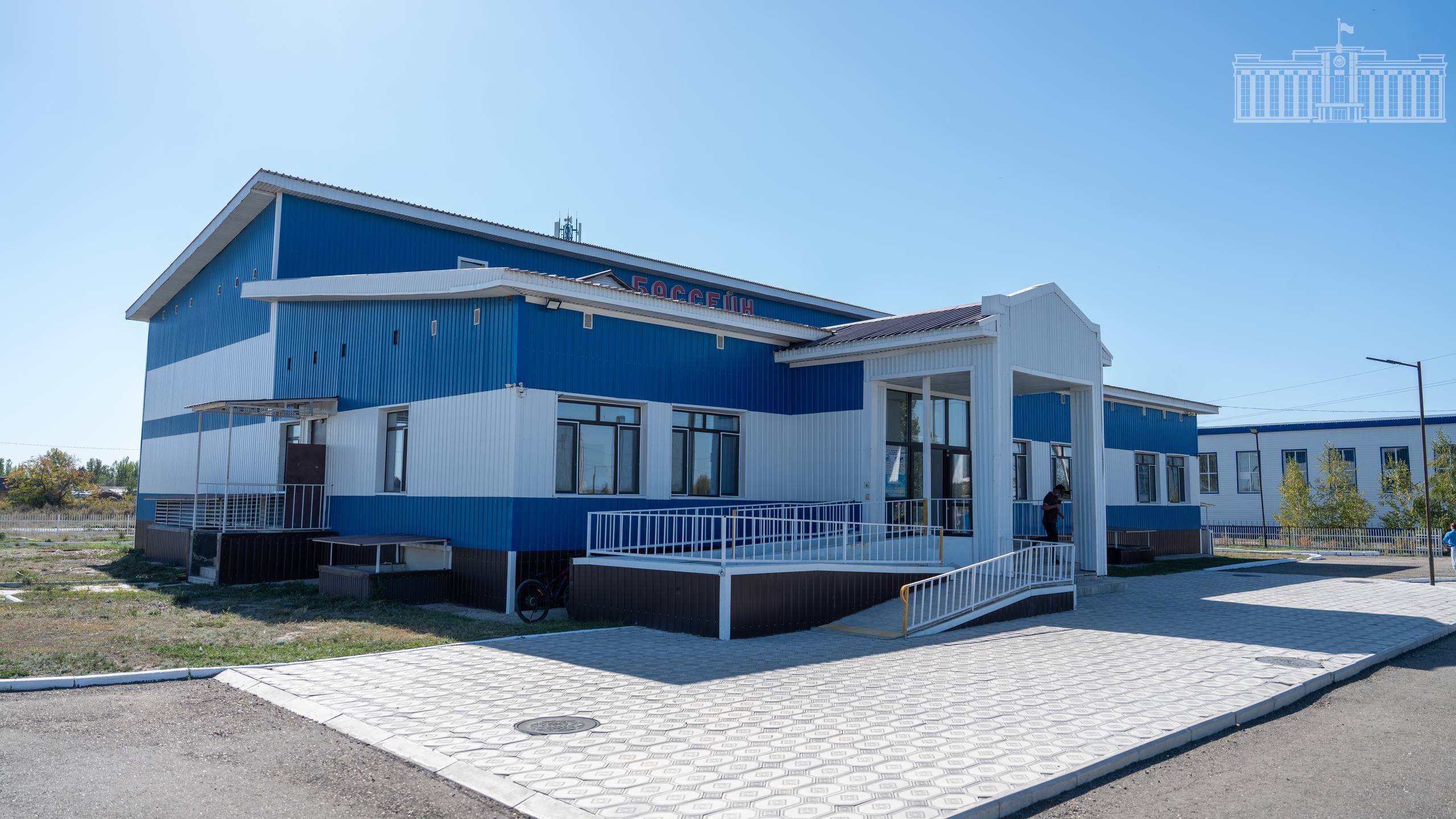 Көк және ақ түсті бір қабатты заманауи ғимарат.