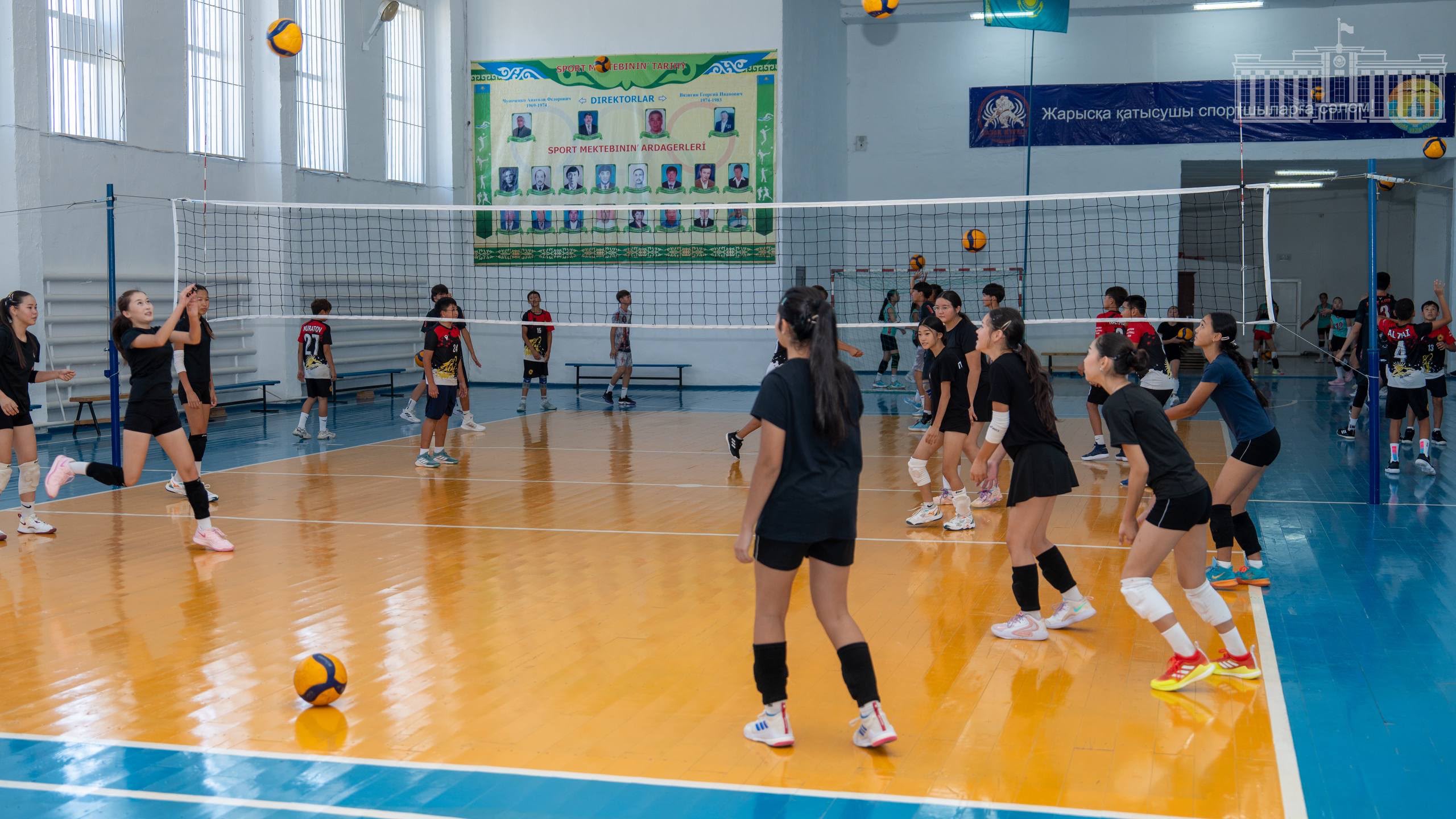 Спорт залында волейбол ойнап жатқан қыздар командасы.