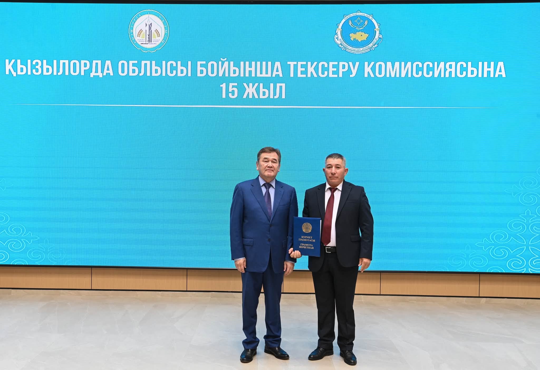 Қызылорда облысы бойынша тексеру комиссиясының 15 жылдығында екі ер адамның грамотамен түсігілген суреті.