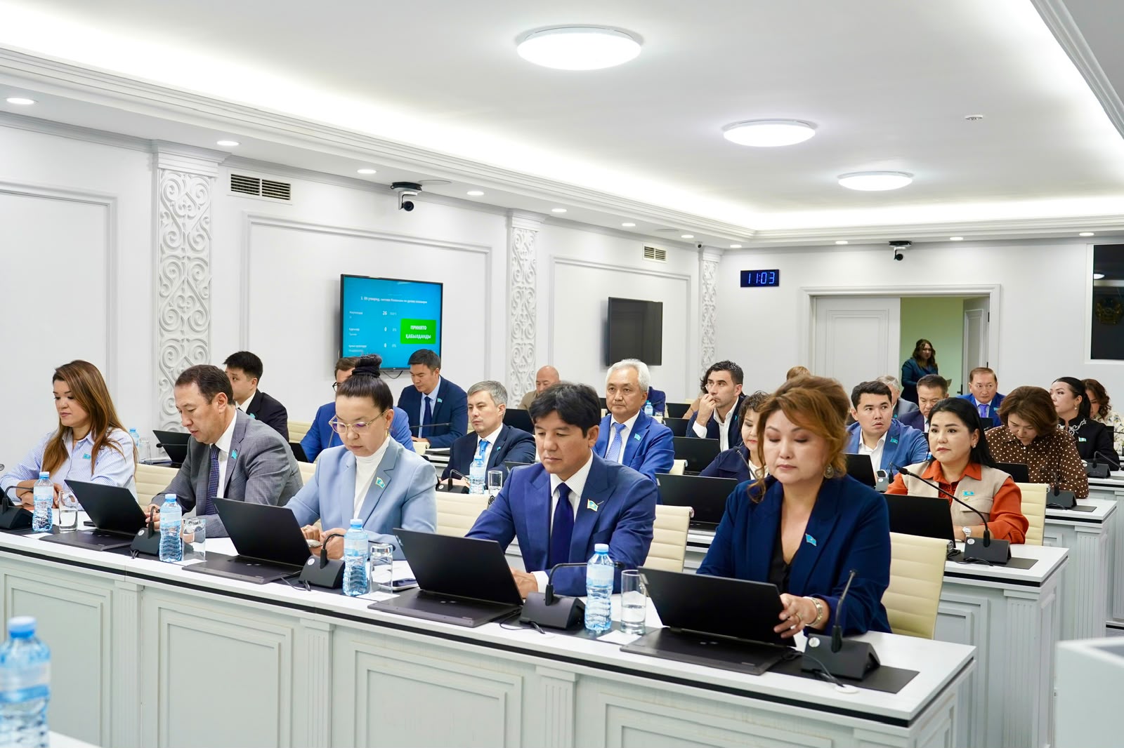 Жиналыс залында ноутбуктермен жұмыс істеп отырған қатысушылар.