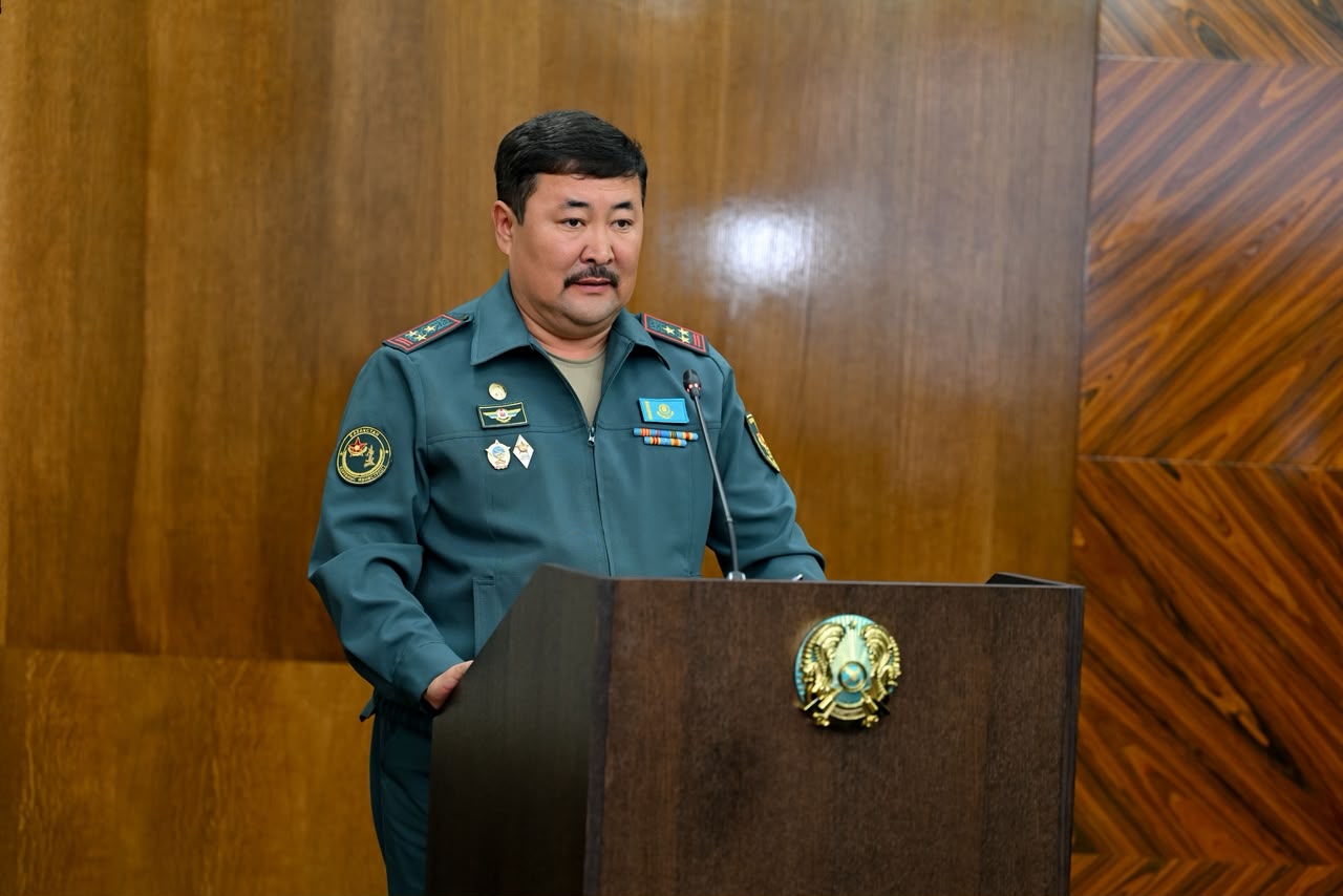 Трибунада тұрған әскери формадағы ер адам.