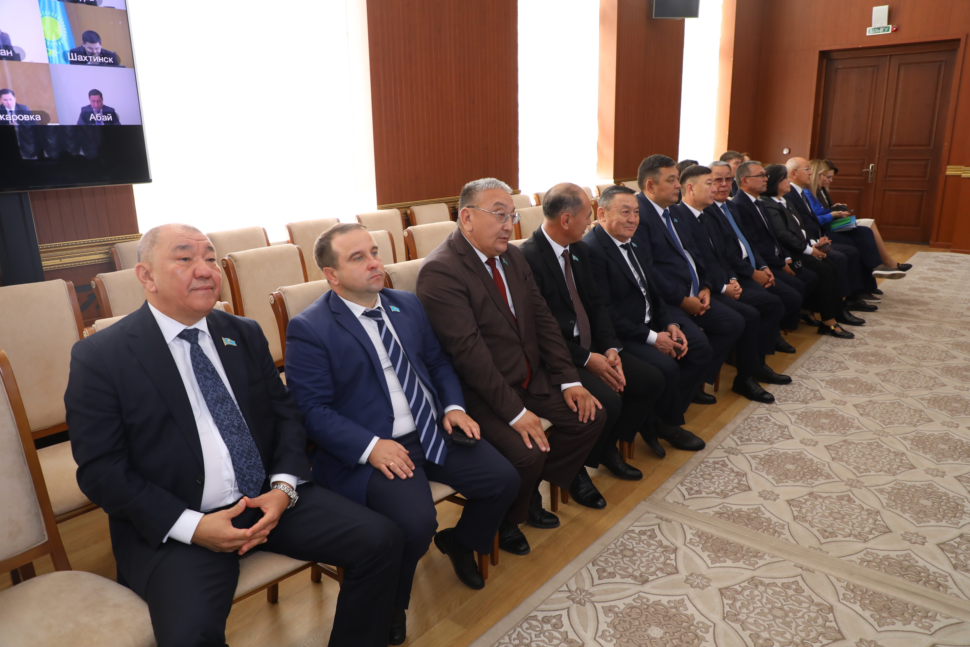 Костюм киген ер адамдардың жиналыста қатар отыруы.