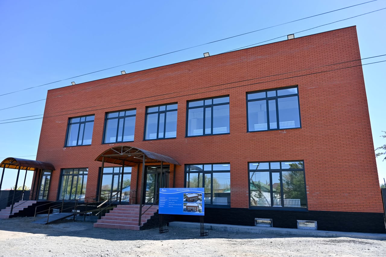 Қызыл кірпіштен салынған екі қабатты заманауи ғимарат.