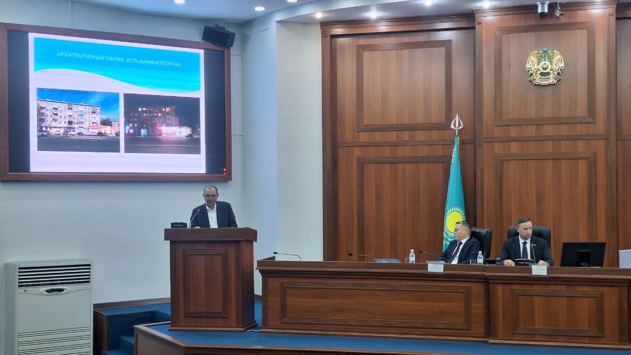 Конференция залындағы баяндама: экранда Өскемен қаласының сәулеттік бейнесі көрсетілген.