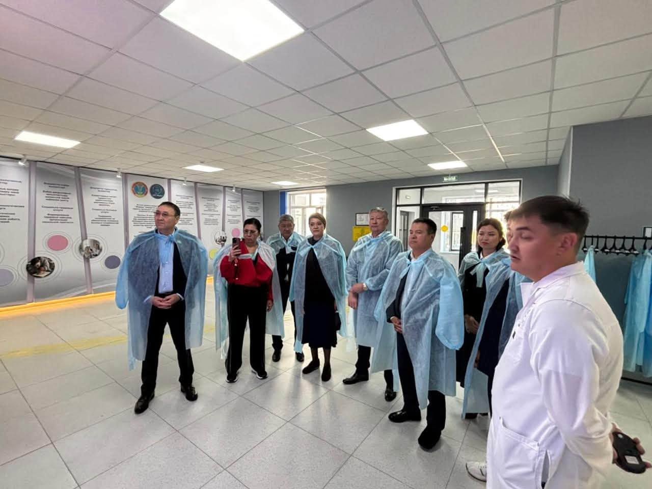 Көк түсті бірреттілік шапан киген адамдар тобы және ақ халатты маман.
