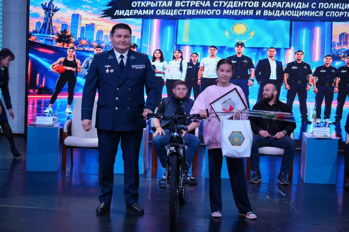 Қарағанды қаласы полиция басқармасының бастығы Шахназар Салин мен грамота ұстаған қыз баланың сахнадағы суреті.