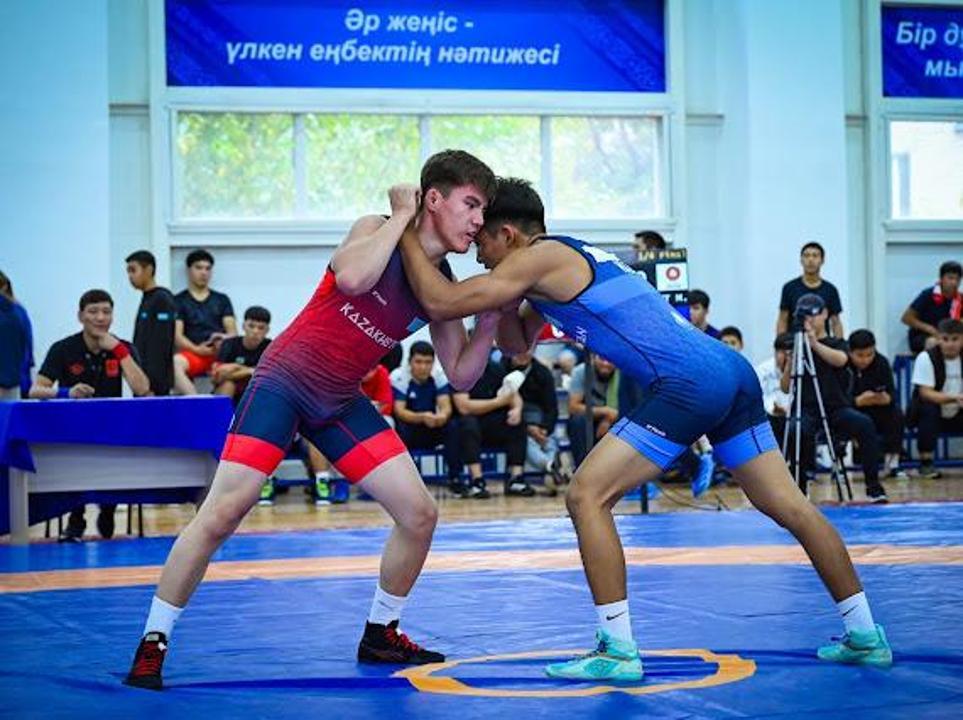 Күрес жарысындағы екі спортшының айқасы.