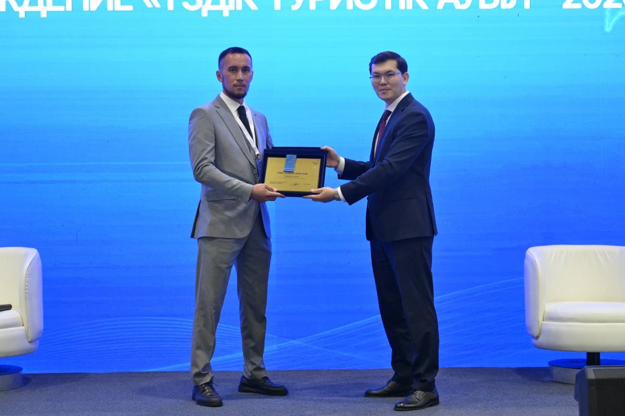 Костюм киген ер адамның сахнада сертификат табыстасу сәті.
