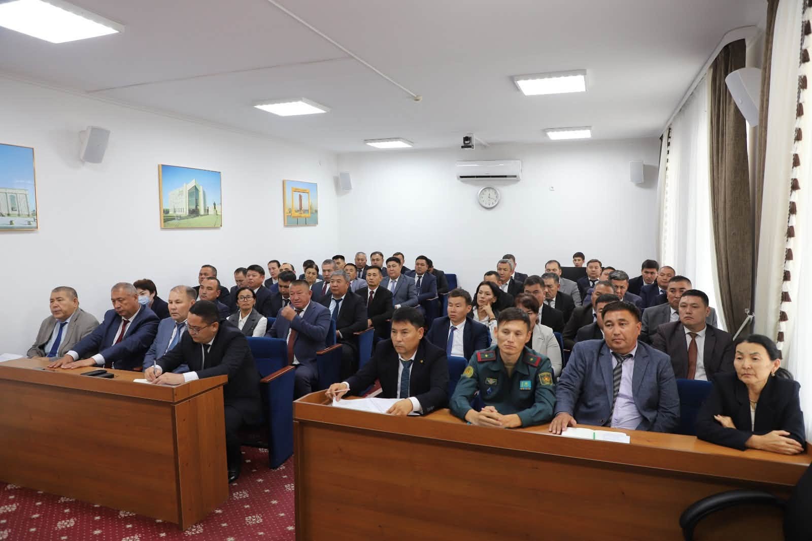 Группа мужчин и женщин в деловых костюмах и форме на официальном собрании в конференц-зале.
