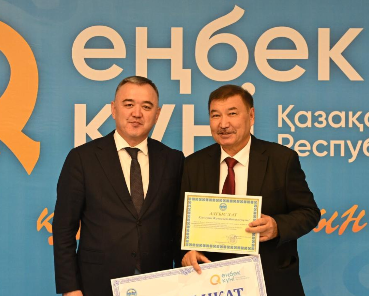 Еңбек күні қарсаңында марапатталып жатқан екі ер адам.