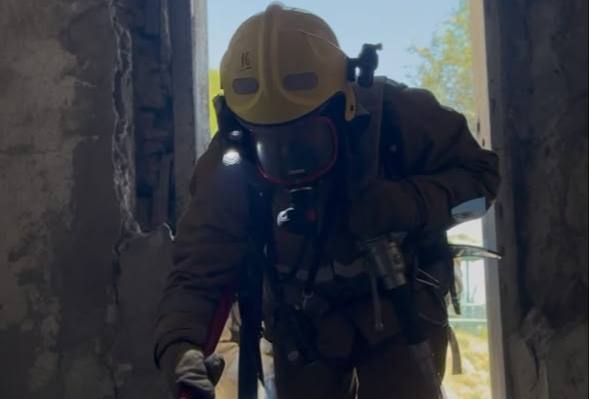 Арнайы киімі мен шлем киген құтқарушының ғимарат ішіндегі бейнесі.