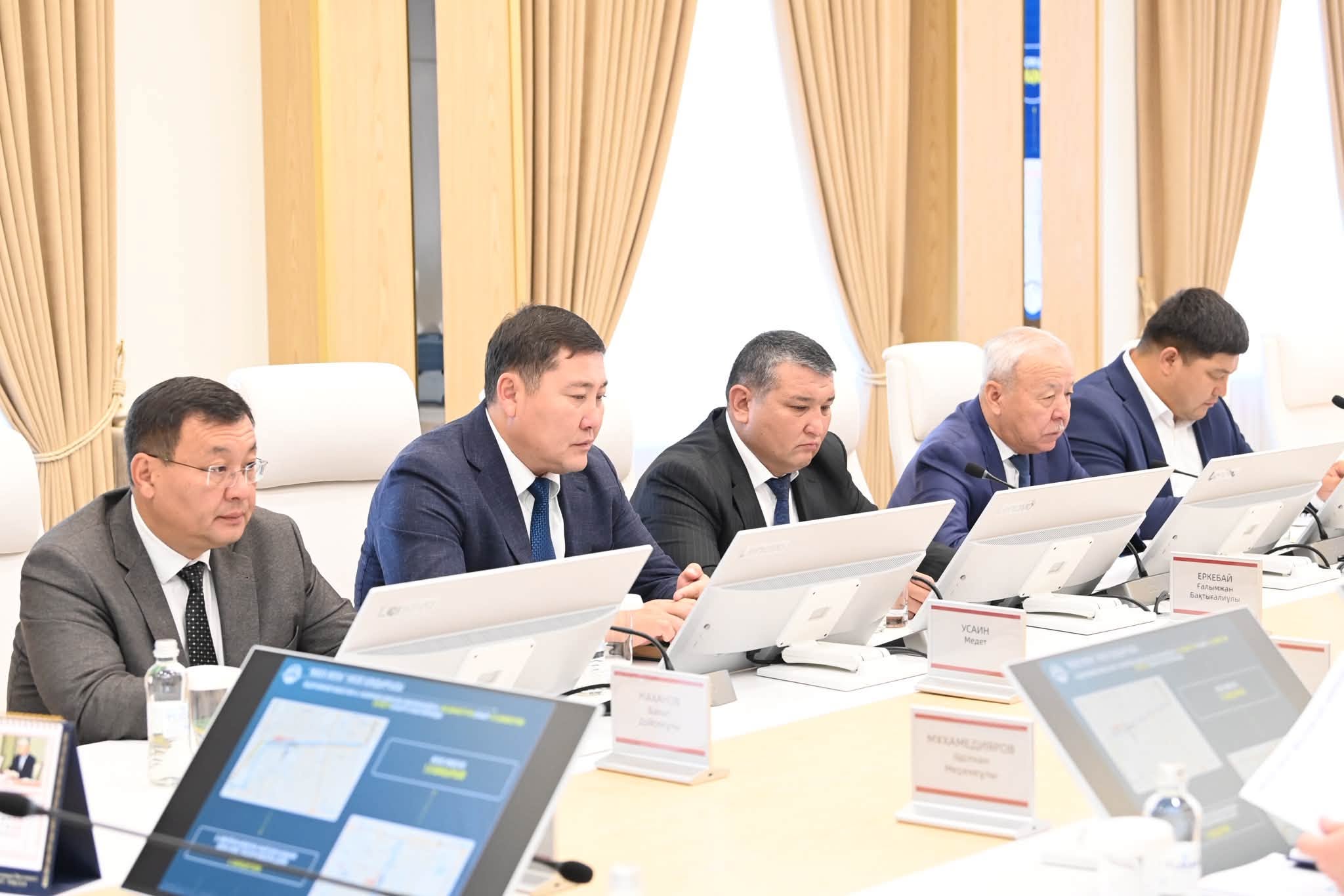 Костюм киген ер адамдар ноутбуктермен жұмыс істеп, жиналыста отыр.
