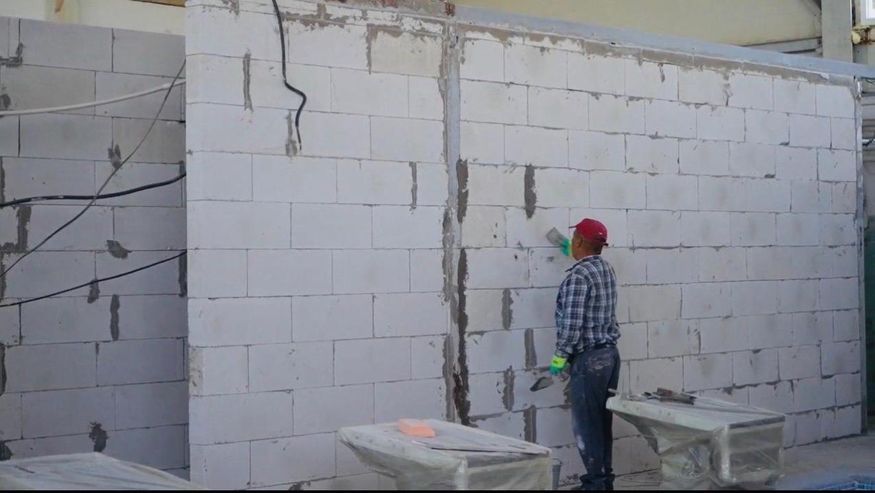 Газблоктан қабырға тұрғызып жатқан құрылыс жұмысшысы.