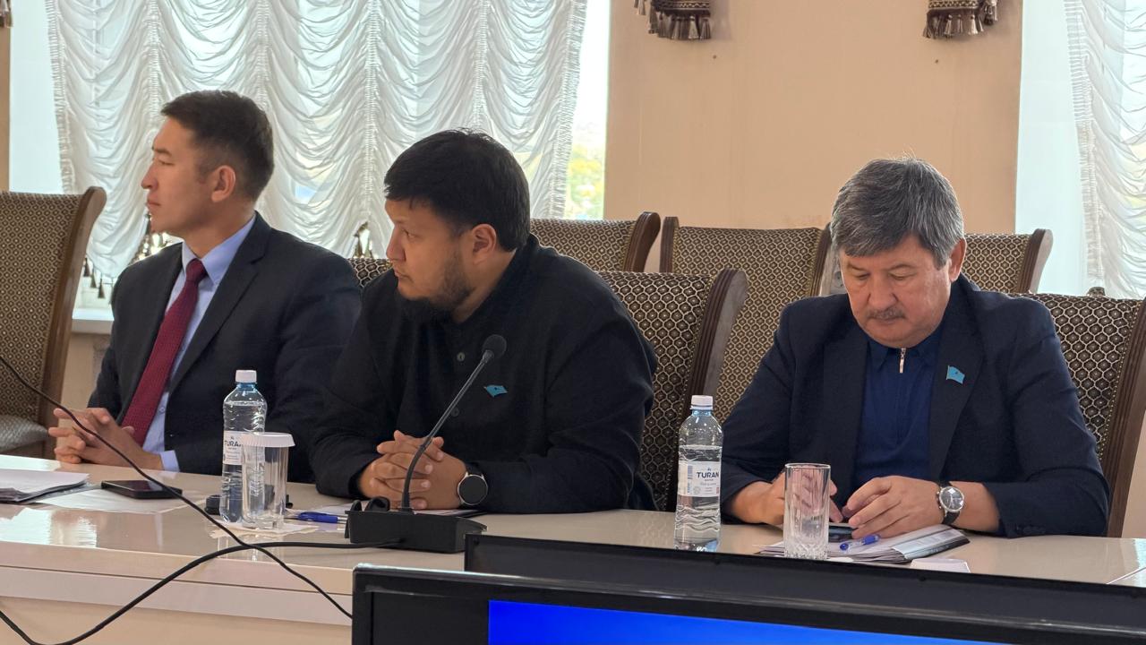 Үстел басында отырған үш ер адам.
