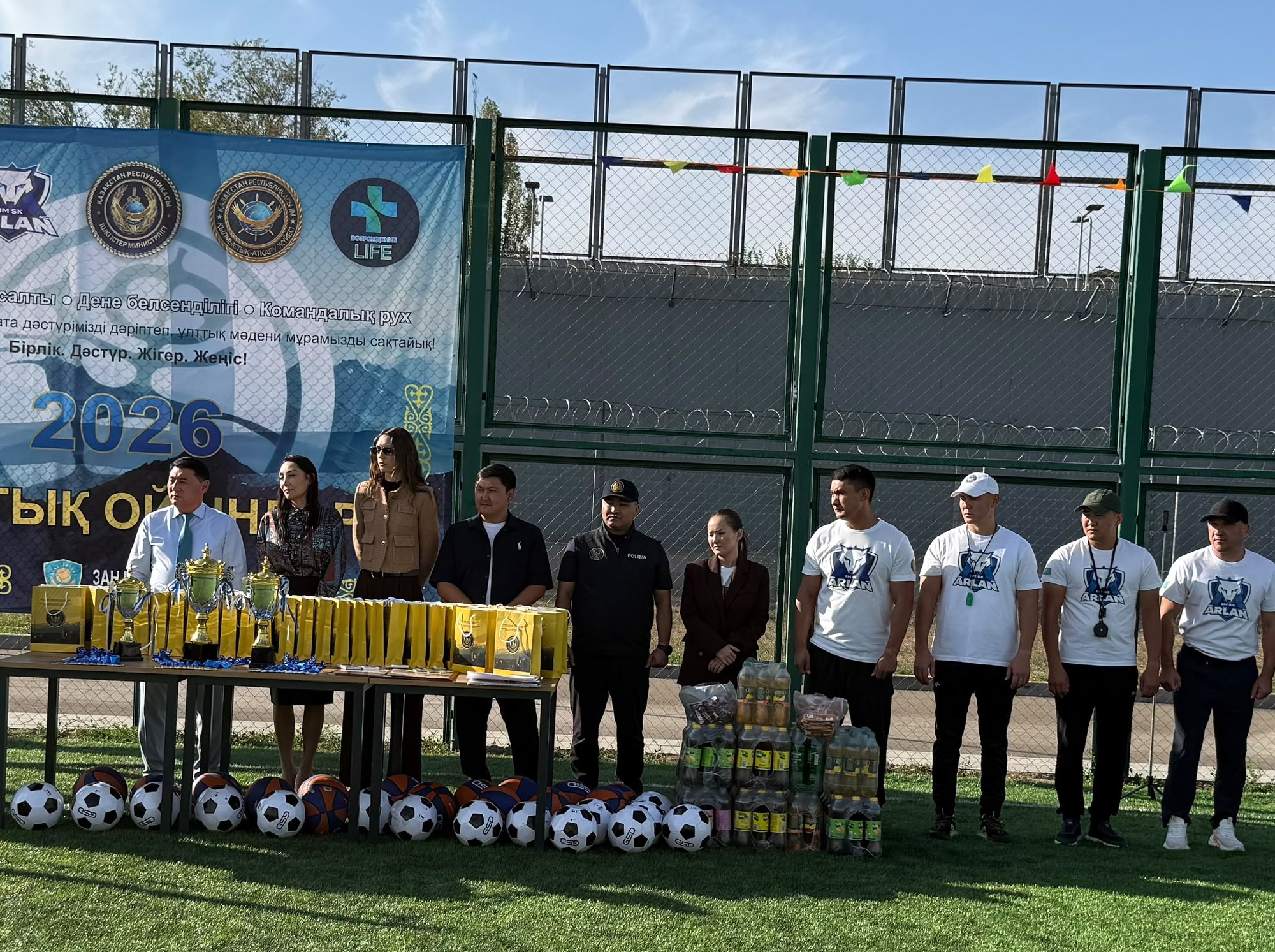 Спорттық іс-шараның наградалау рәсімі: ұйымдастырушылар мен сыйлықтардың алдында тұрған топ.