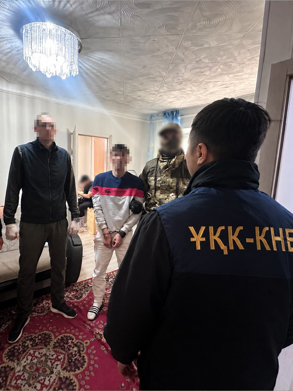 Қолы байланған күдікті мен оны күзетіп тұрған құқық қорғау органдарының қызметкерлері.