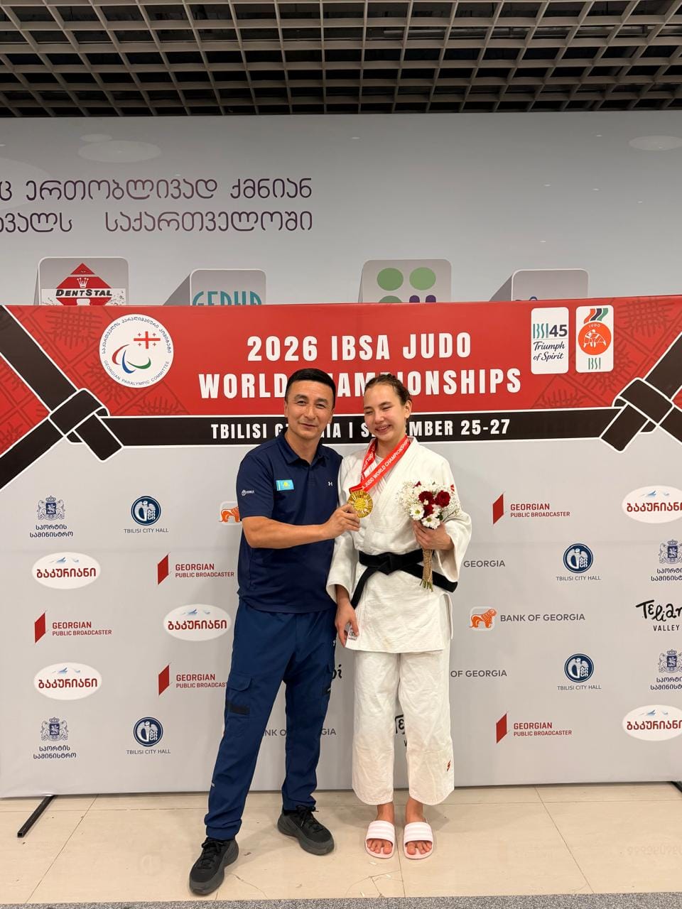 2026 жылғы IBSA дзюдо әлем чемпионатында алтын медаль алған спортшы мен жаттықтырушы.