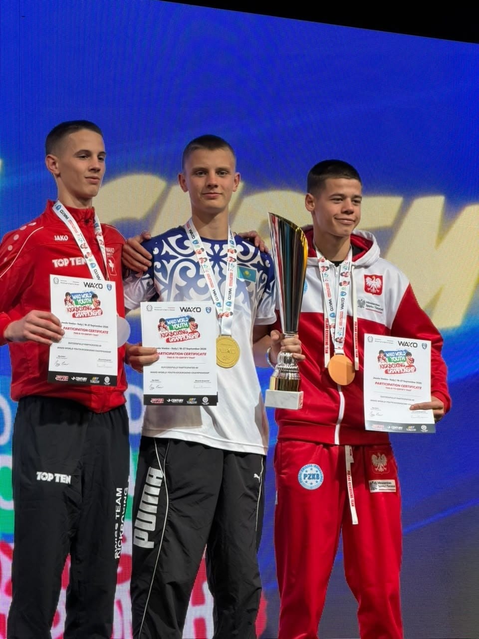 WAKO жастар әлем чемпионатының жеңімпаз үш спортшысы: алтын, күміс және қола медаль иелері кубок пен сертификаттармен.