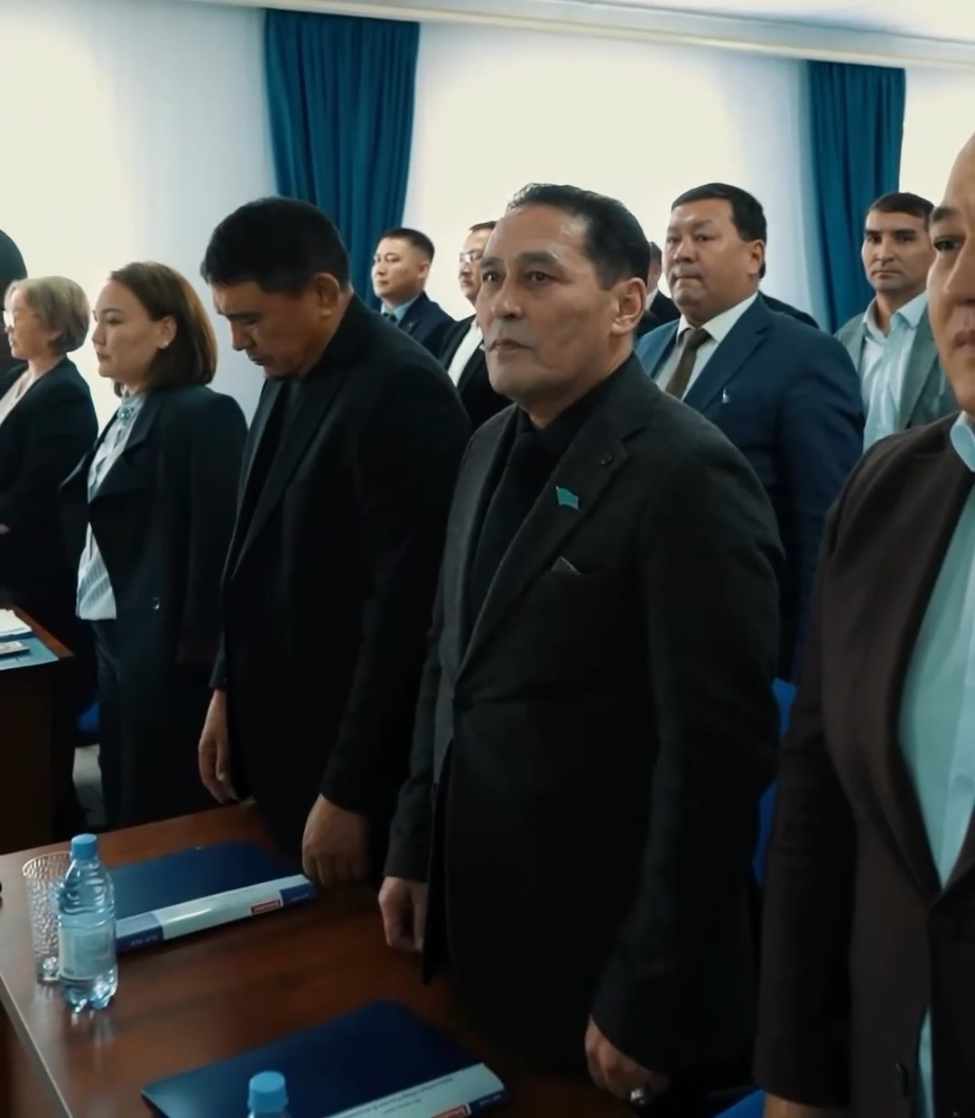 Ресми киімдегі адамдардың жиналыста тұрған сәті.