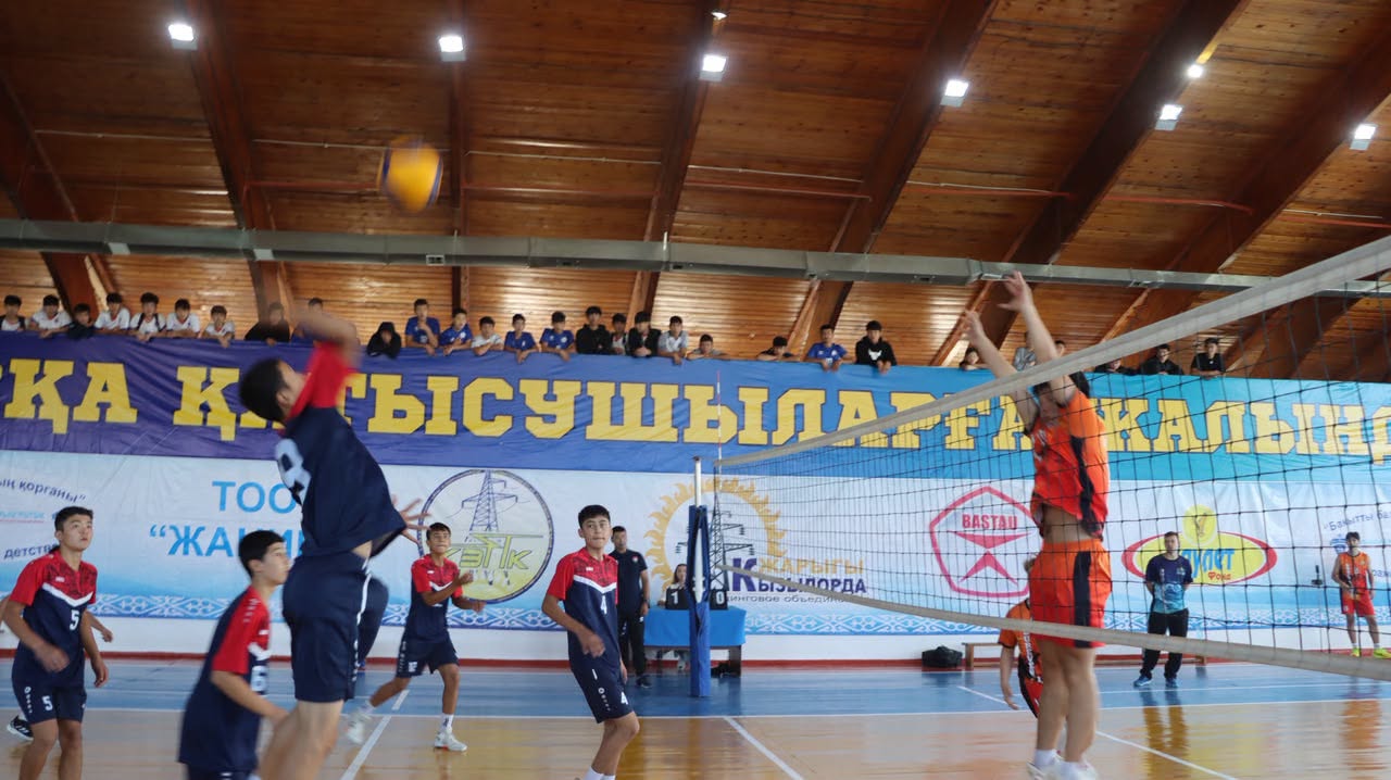 Волейболисты в спортивной форме играют матч в закрытом спортзале.