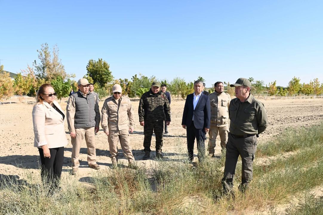 Ашық алаңда жиналған ресми киімді және әскери формадағы адамдар тобы.