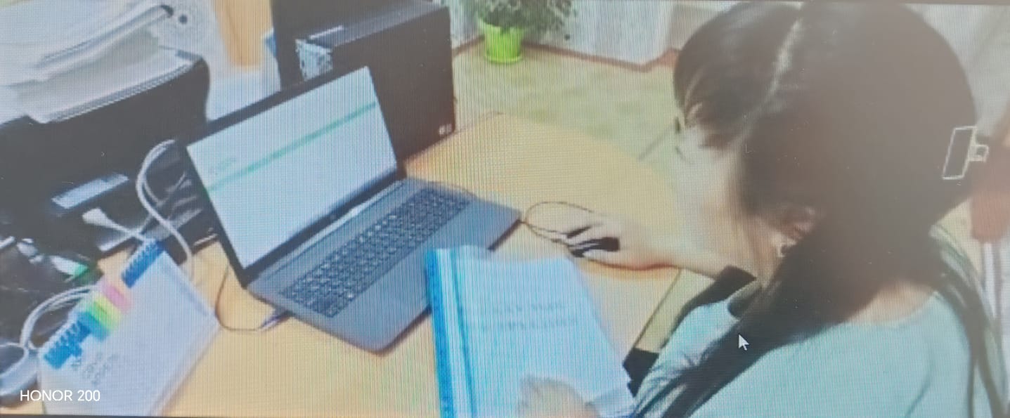 Ноутбук пен дәптермен жұмыс істеп отырған қыз.