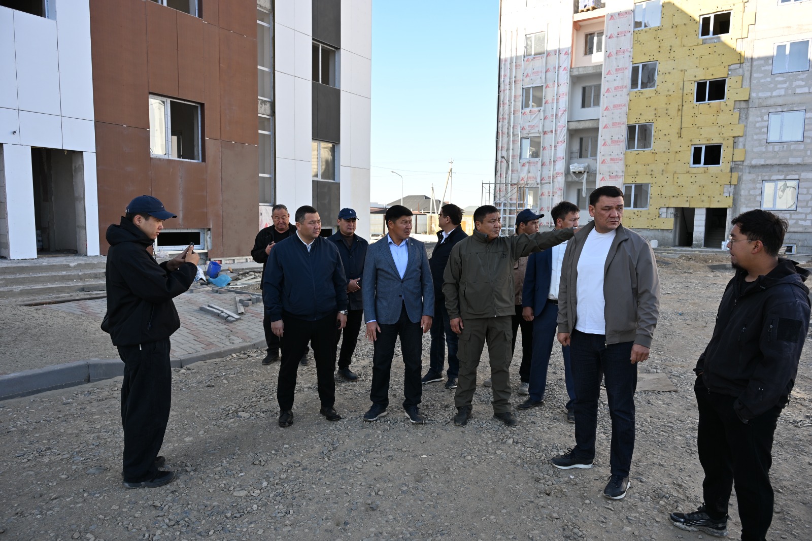 Құрылыс алаңында жиналған ерлер тобының әңгімелесуі.