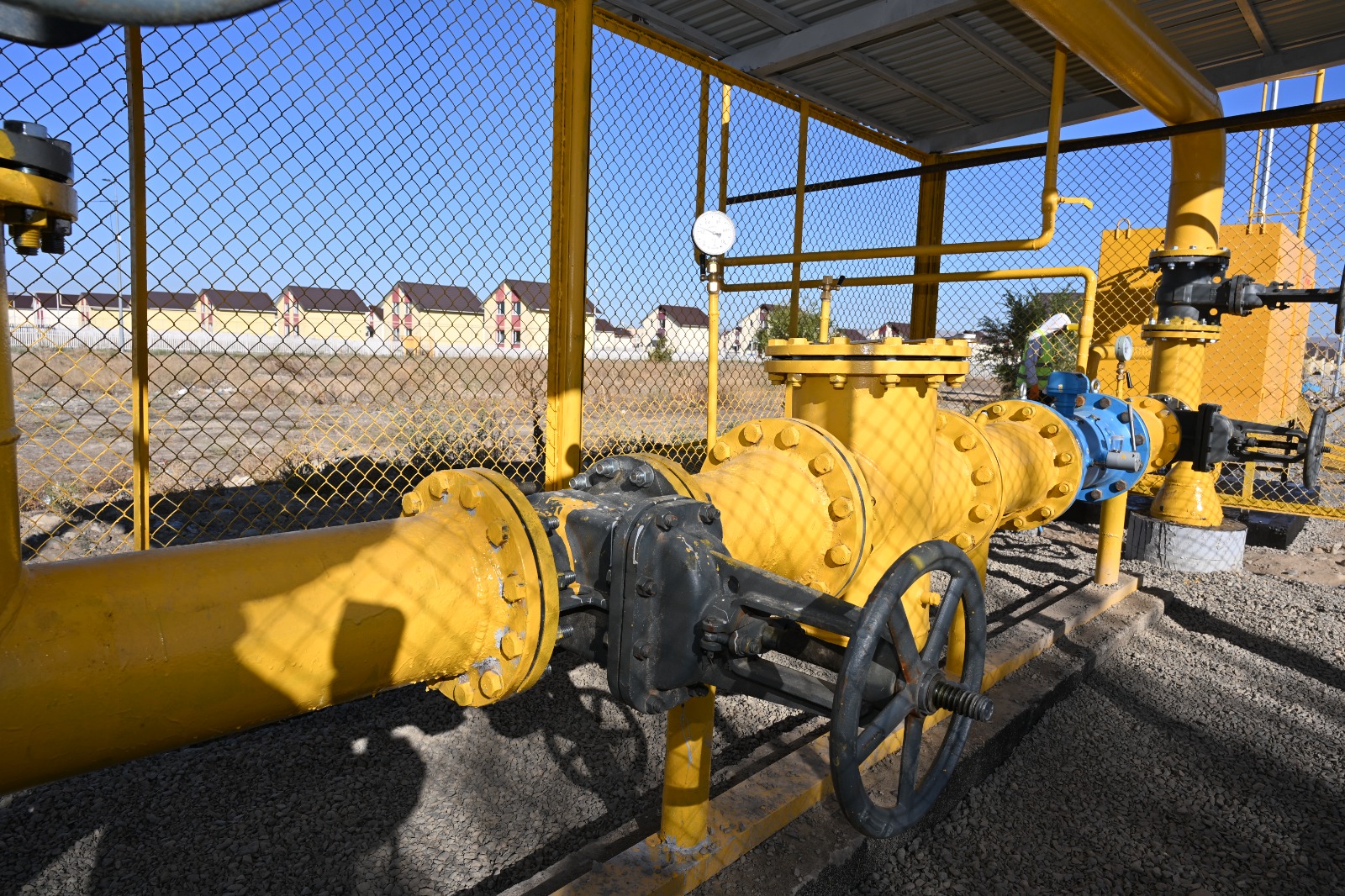 Сары түсті газ құбыттары мен вентильдері бар газ distribution станциясы.