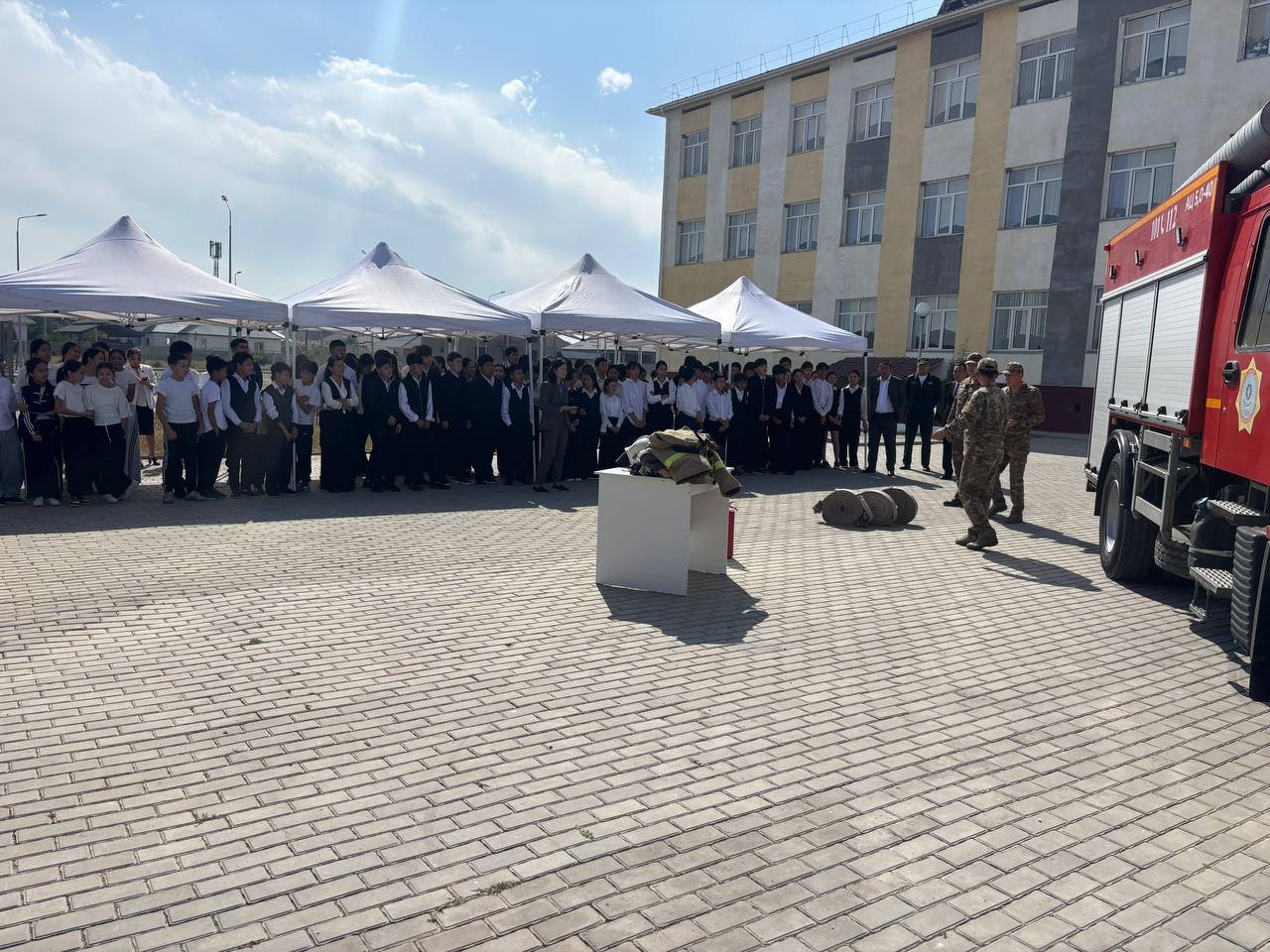 Мектеп ауласындағы өрт сөндіру қызметінің көрсетіліміне жиналған оқушылар мен әскери мамандар.