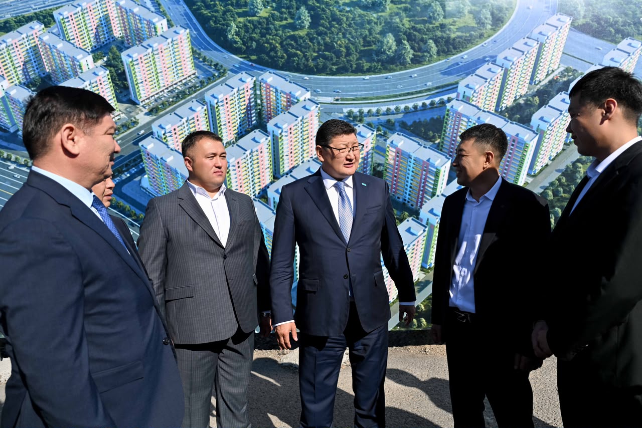 Костюм киген ер адамдар тобы жаңа тұрғын үй кешенінің жобасы алдында тұр.