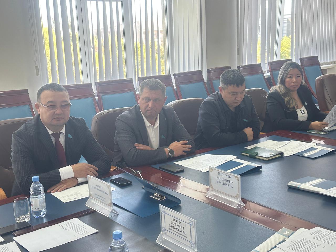 Жиналыс үстелінде отырған төрт адам.