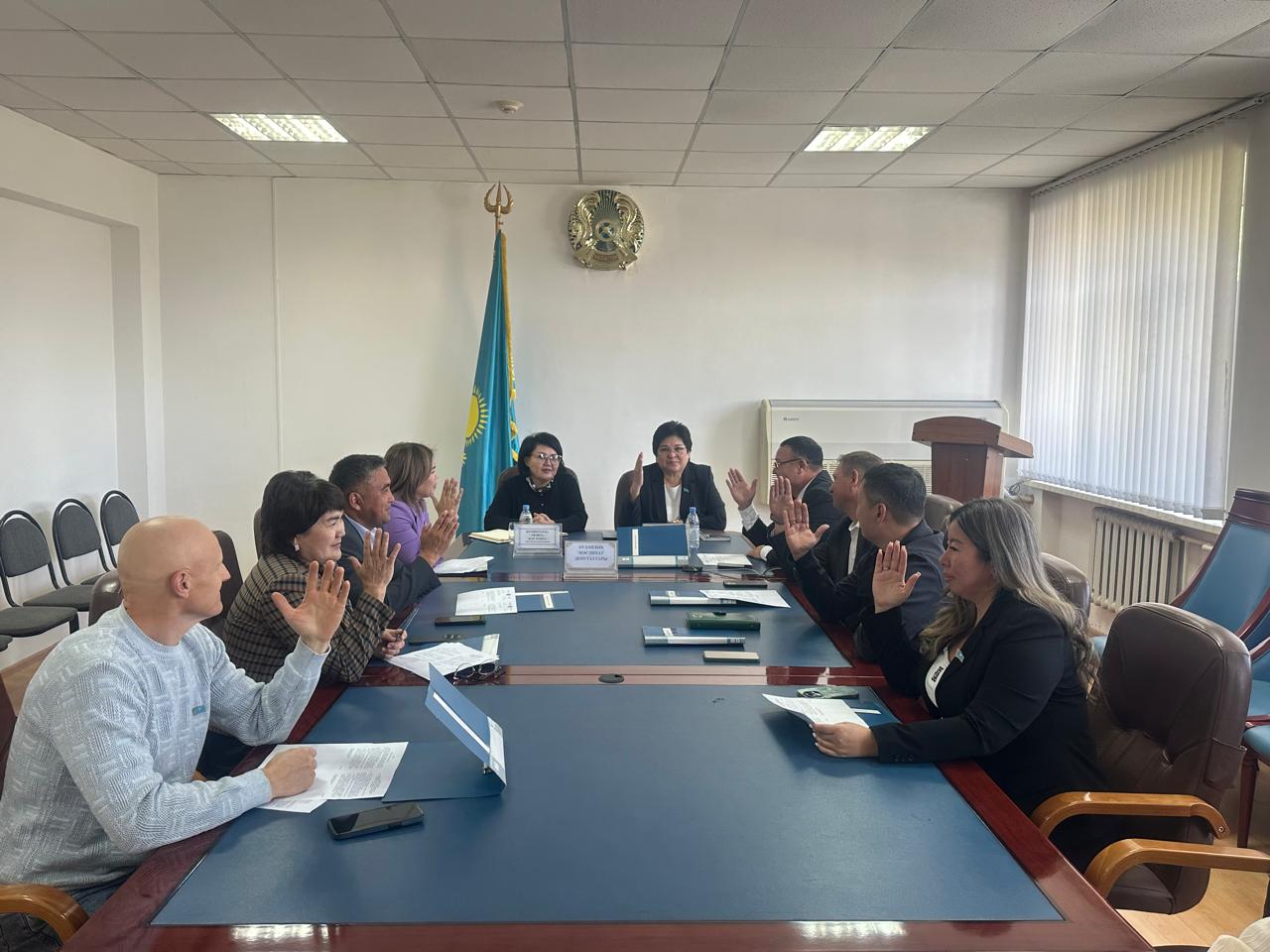 Келіссөз үстелінде жиналған адамдар дауыс беріп жатыр.