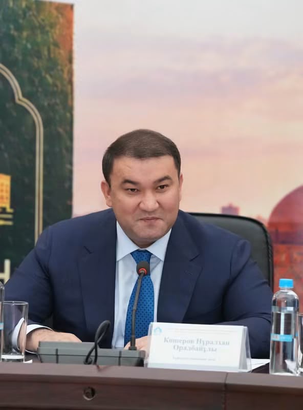 Көк костюм киген, үстел басында отырған Қөтеров Нұрланхан Оралбайұлы.