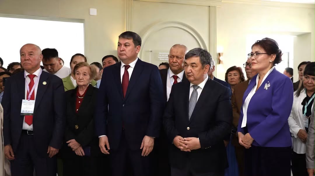 Ресми киімдегі адамдар тобы жиналыста тұр.
