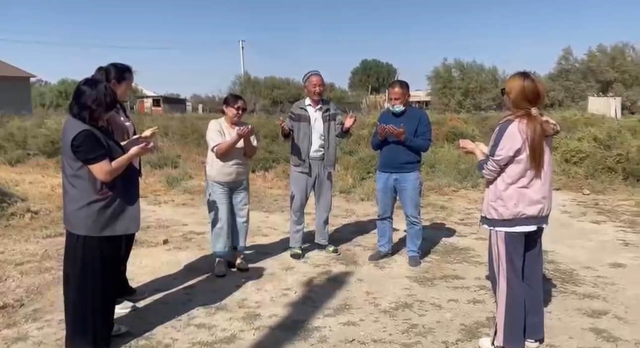 Ашық аспан астында жиналған, әңгімелесіп тұрған адамдар тобы.