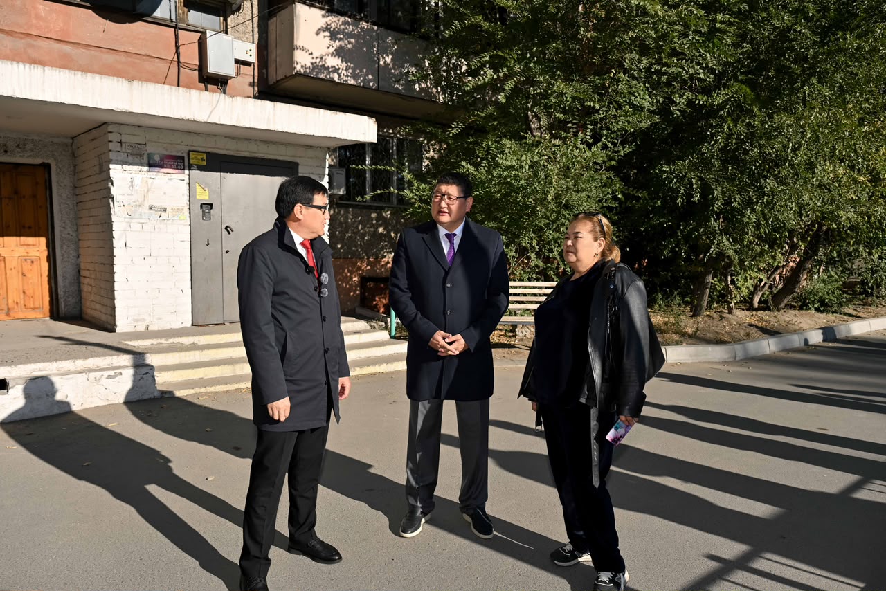 Ғимарат алдында тұрған үш адамның әңгімелесуі.