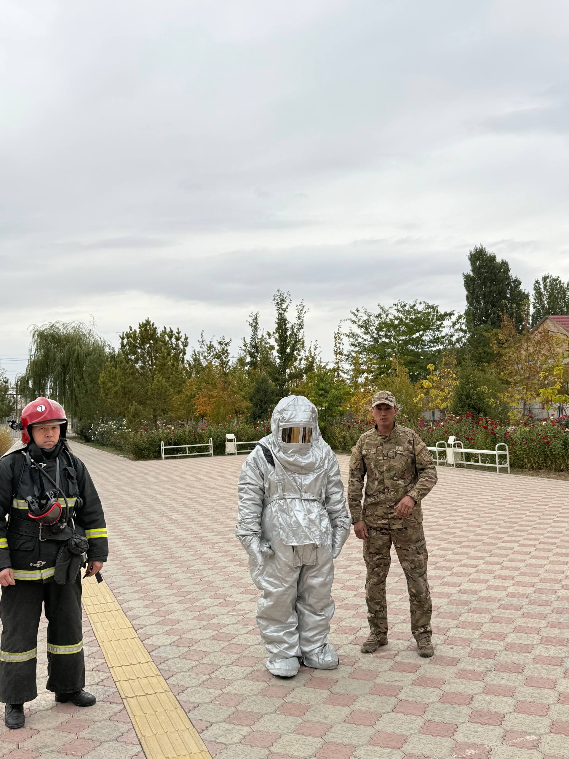 Өрт сөндіруші, арнайы жылуға төзімді костюм киген маман және әскери формадағы сарбаз.