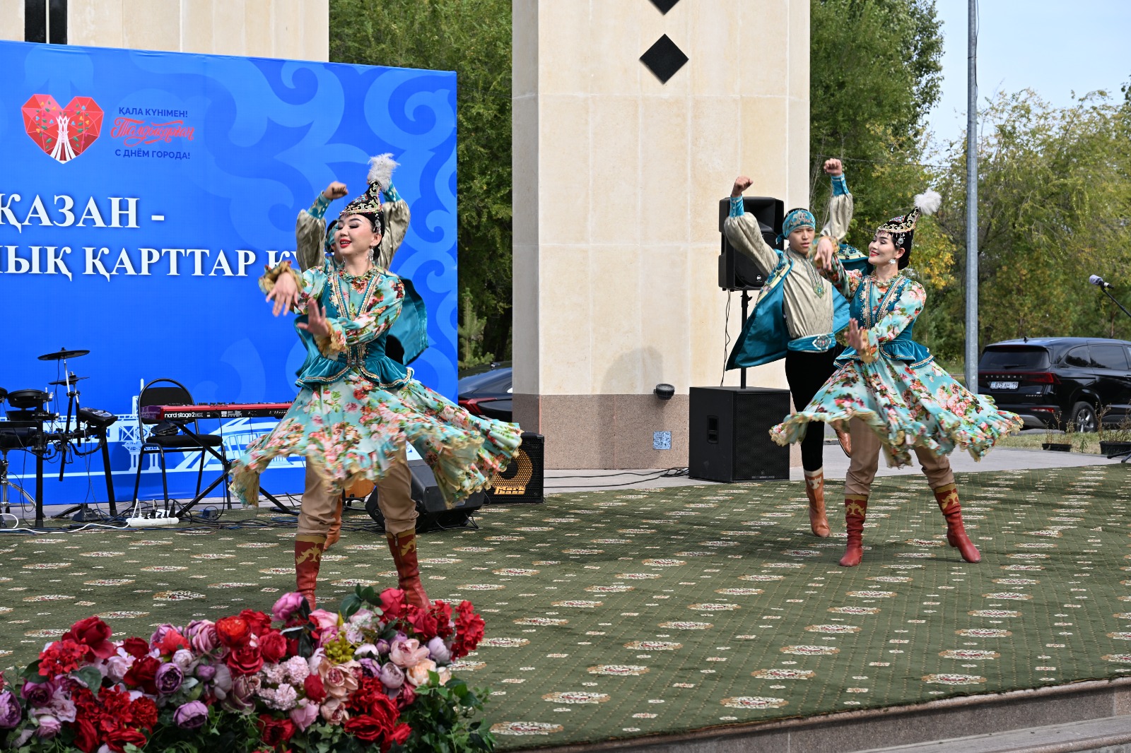 Ұлттық киім киген бишілердің сахнадағы қойымы.
