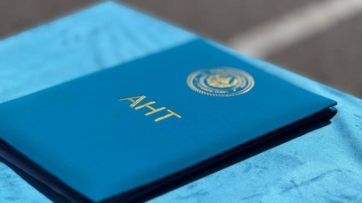 АНТ жазуы бар көк папка үстел үстінде жатыр
