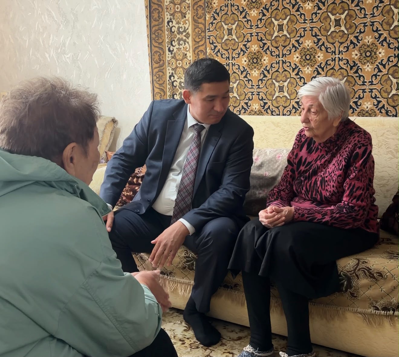 Костюм киген жас жігіттің екі қарт әйелмен сөйлесіп отырғаны.