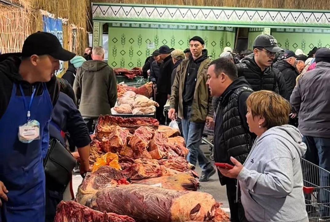 Ет базарындағы сатып алушылар мен сатушылар. Үстел үстінде жайылып жатқан ет өнімдері.