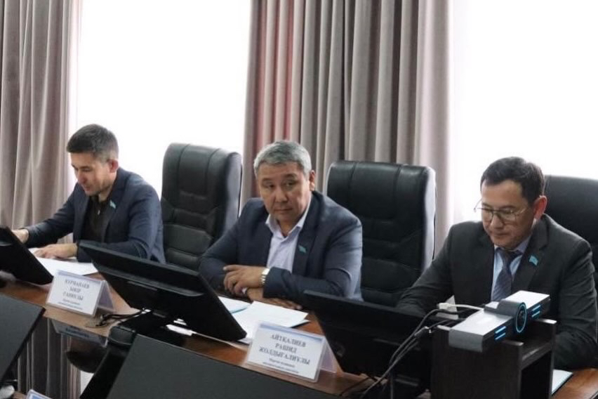 Жиналыста үстел басында отырған үш ер адам.