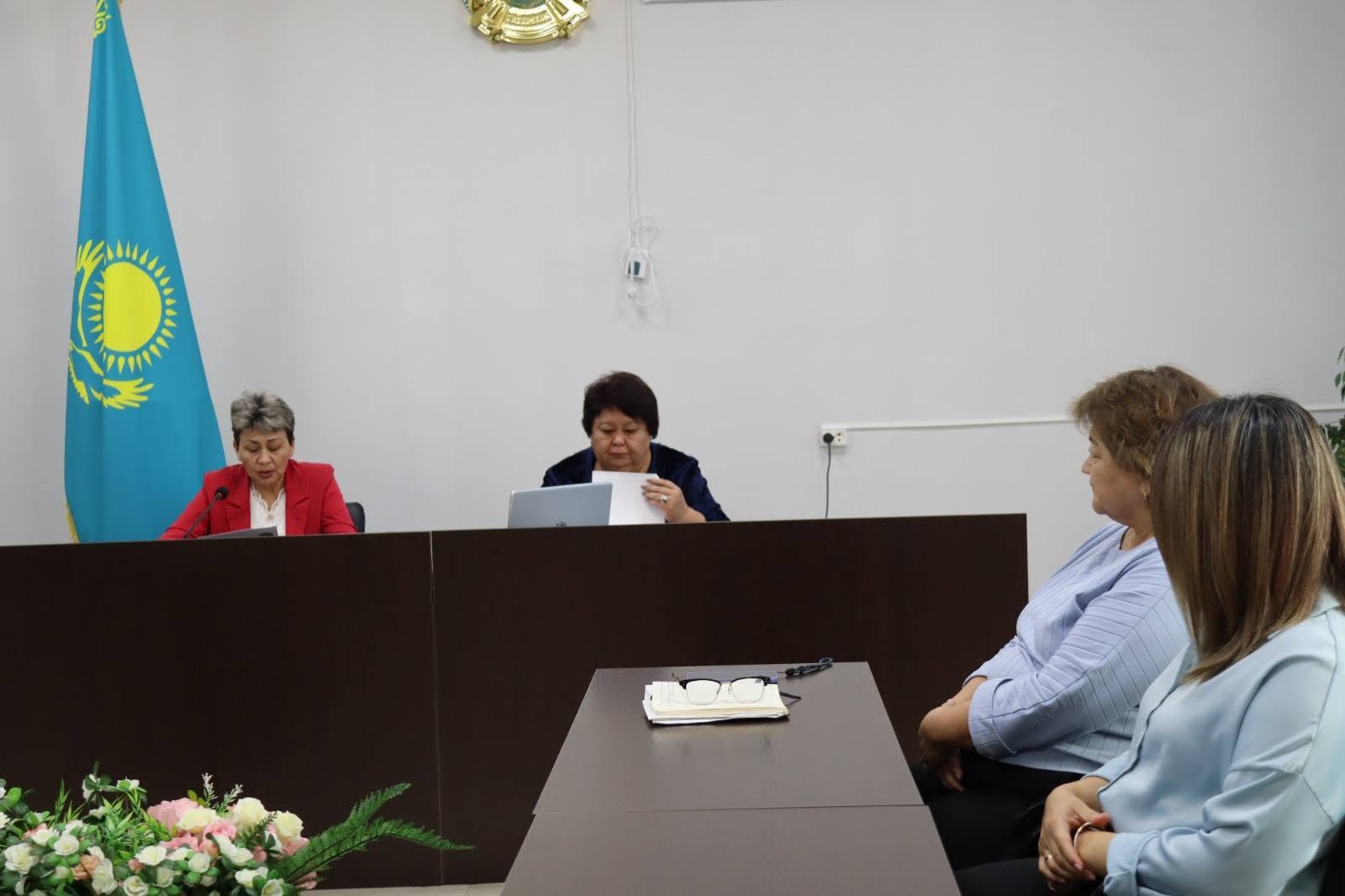 Қазақстан туы тұрған бөлмеде өткізіліп жатқан ресми жиналыс немесе кеңес.